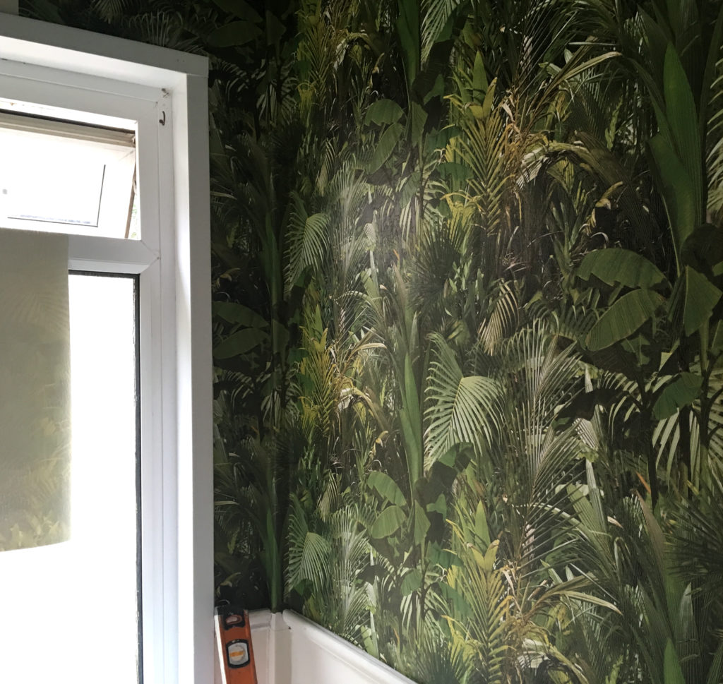 The wallpapering of the first wall of the downstairs loo complete